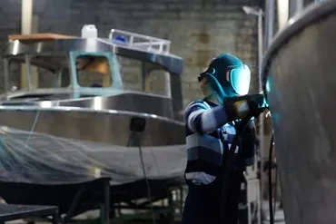 Welder working on aluminum boat in marine workshop