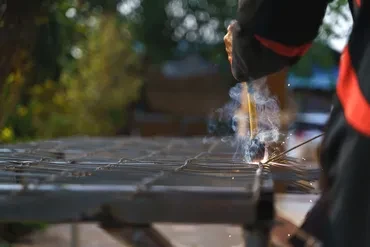 Welder working on metal fence panel outdoors