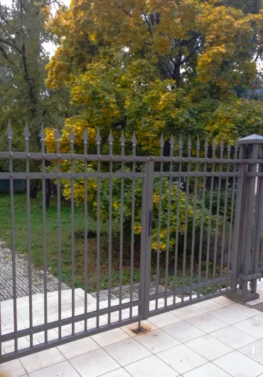 Completed iron fence installation with autumn trees