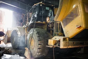 Large wheel loader and dump truck inside industrial repair facility