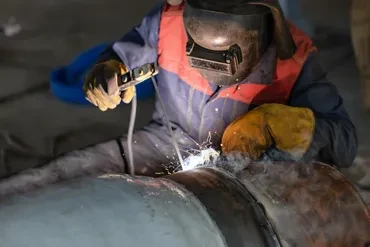 Precision welding on metal shaft component with sparks close-up